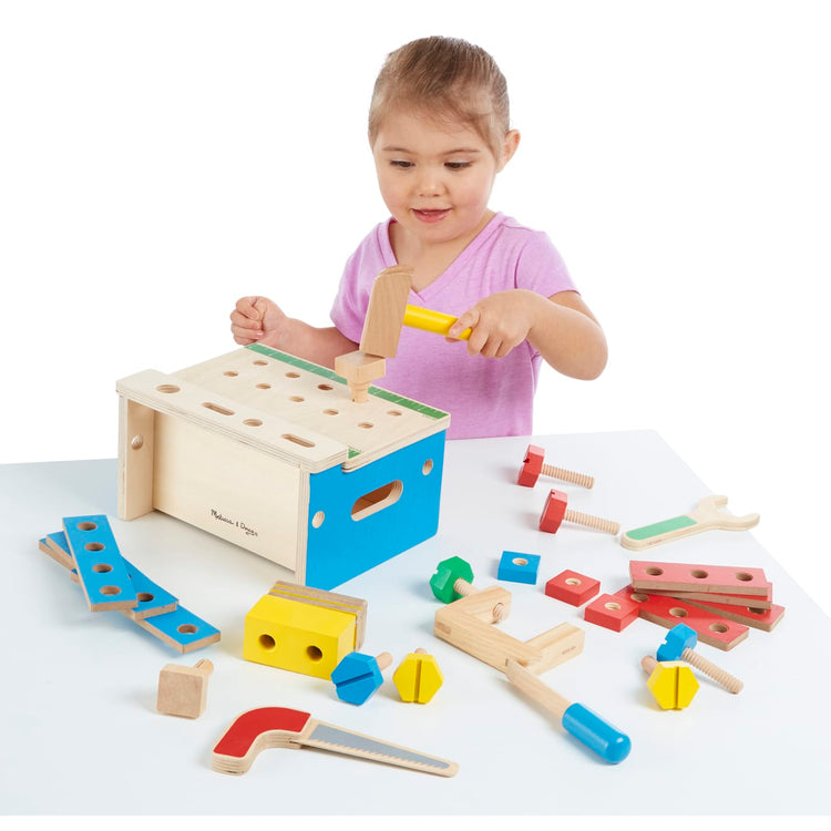 A child on white background with the Melissa & Doug Hammer and Saw Tool Bench - Wooden Building Set (32 pcs)