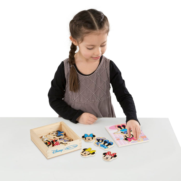 A child on white background with the Melissa & Doug Disney Minnie Mouse Mix and Match Dress-Up Wooden Play Set (18 pcs)