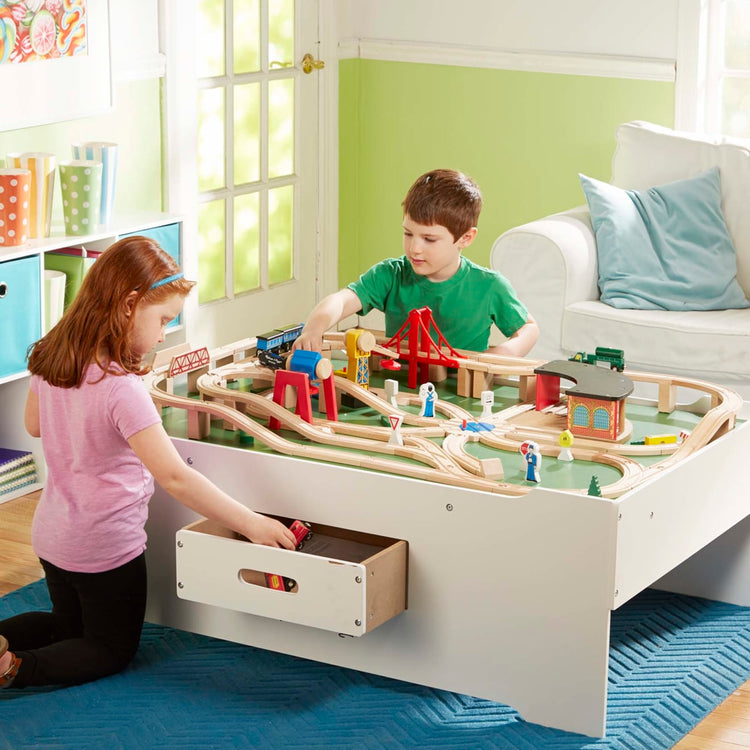 A kid playing with the Melissa & Doug Deluxe Wooden Multi-Activity Play Table - For Trains, Puzzles, Games, More