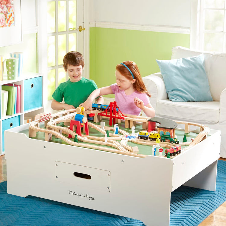 A kid playing with the Melissa & Doug Deluxe Wooden Multi-Activity Play Table - For Trains, Puzzles, Games, More