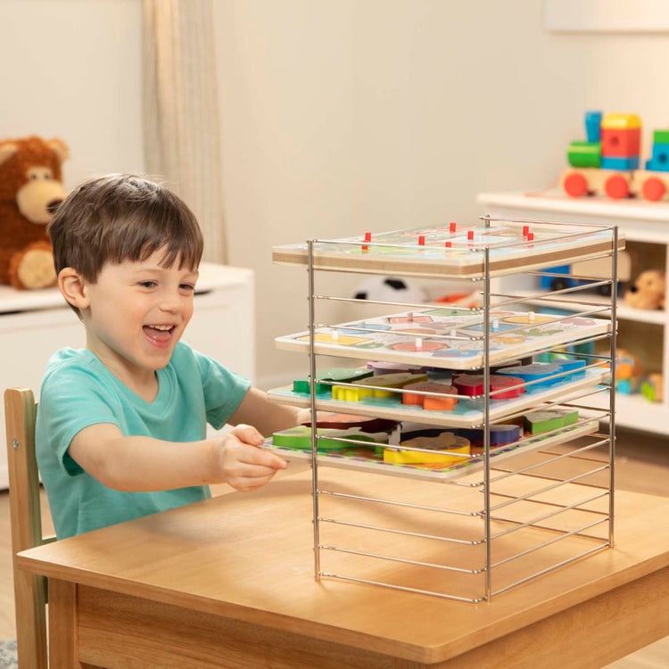A kid playing with the Melissa & Doug Multi-Fit Metal Wire Puzzle Rack For Up To a Dozen 12-Inch-Wide, 0.75-Inch Deep Wooden Puzzles