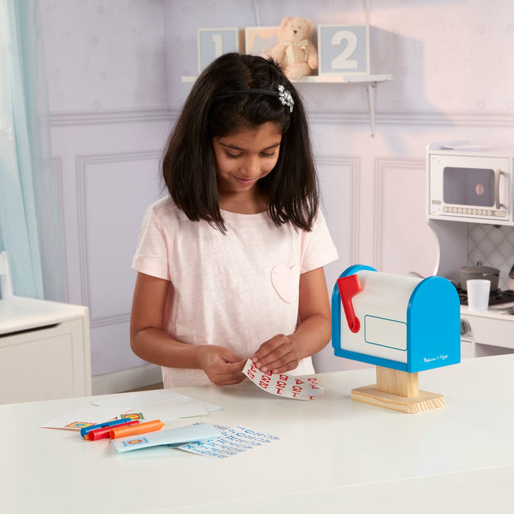 A kid playing with the Melissa & Doug My Own Wooden Mailbox Activity Set and Educational Toy