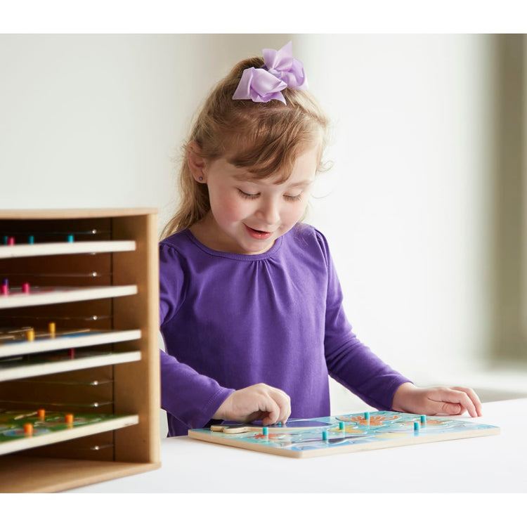 A kid playing with the Melissa & Doug Wooden Puzzle Storage Case (Holds 12 Puzzles)