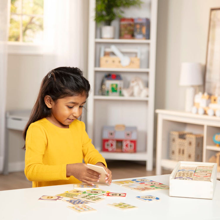 A kid playing with the Melissa & Doug Self-Correcting Wooden Number Puzzles With Storage Box (40 pcs)