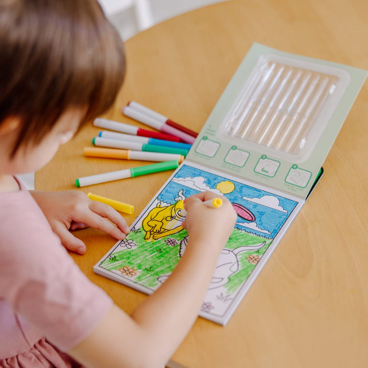 A kid playing with the Melissa & Doug Magic-Pattern Kids’ Pets Marker Coloring Pad On the Go Travel Activity