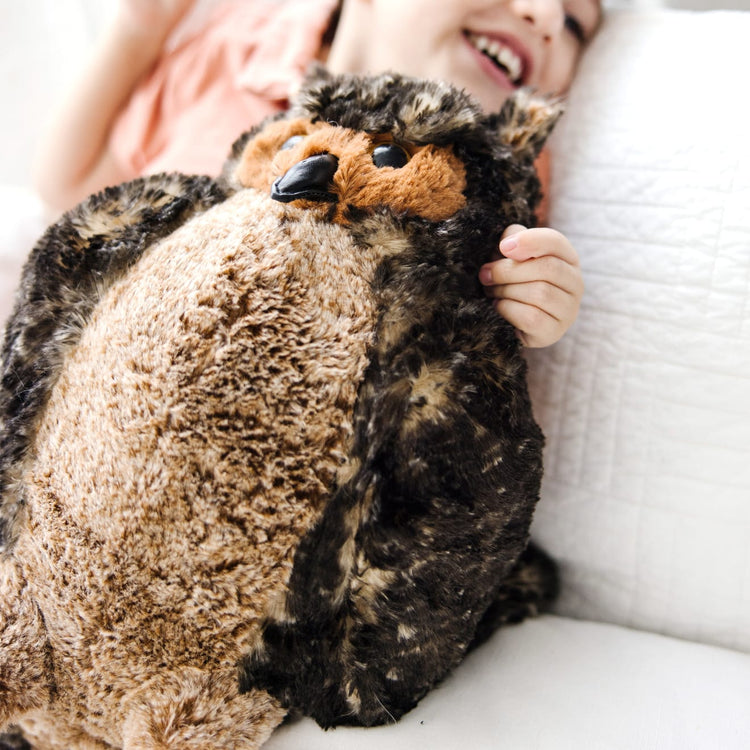 A kid playing with the Melissa & Doug Giant Owl - Lifelike Stuffed Animal (17 inches tall)