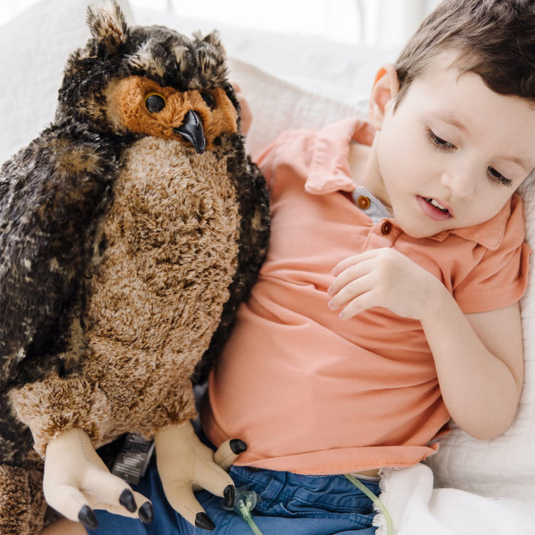 A kid playing with the Melissa & Doug Giant Owl - Lifelike Stuffed Animal (17 inches tall)