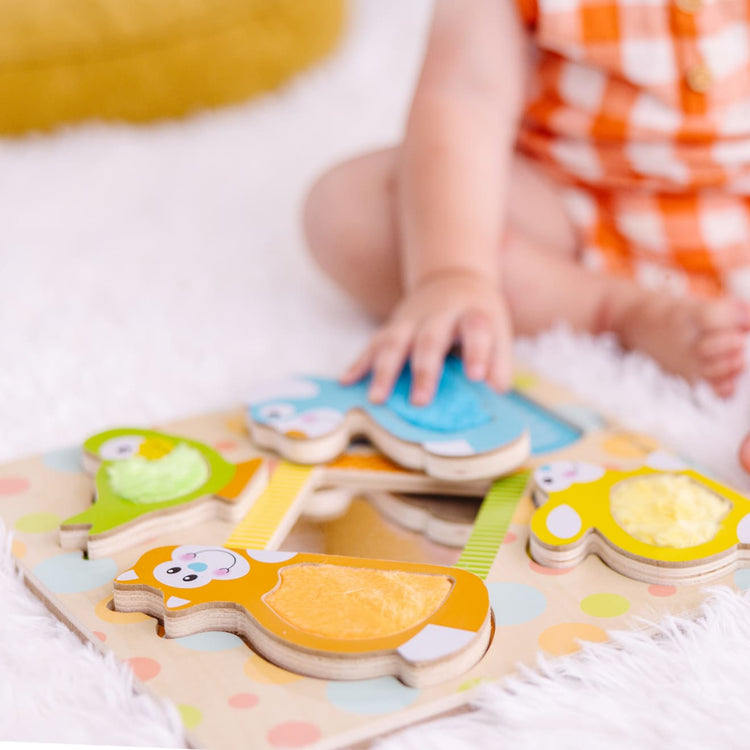 A kid playing with the Melissa & Doug First Play Wooden Touch and Feel Puzzle Peek-a-Boo Pets With Mirror
