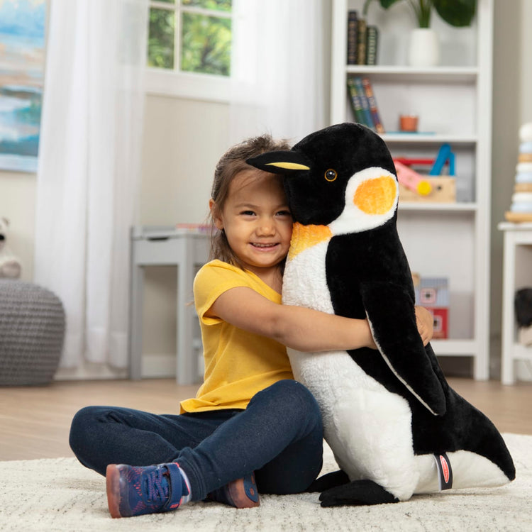 A kid playing with the Melissa & Doug Giant Penguin - Lifelike Stuffed Animal (nearly 2 feet tall)