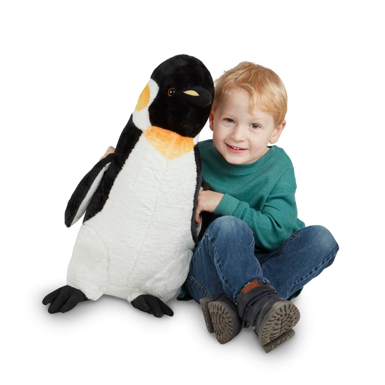 A child on white background with the Melissa & Doug Giant Penguin - Lifelike Stuffed Animal (nearly 2 feet tall)