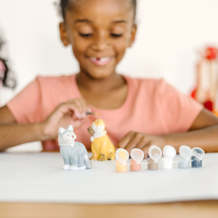 A kid playing with the Melissa & Doug Created by Me! Pet Figurines Craft Kit (Resin Dog and Cat, 6 Paints, Paintbrush)