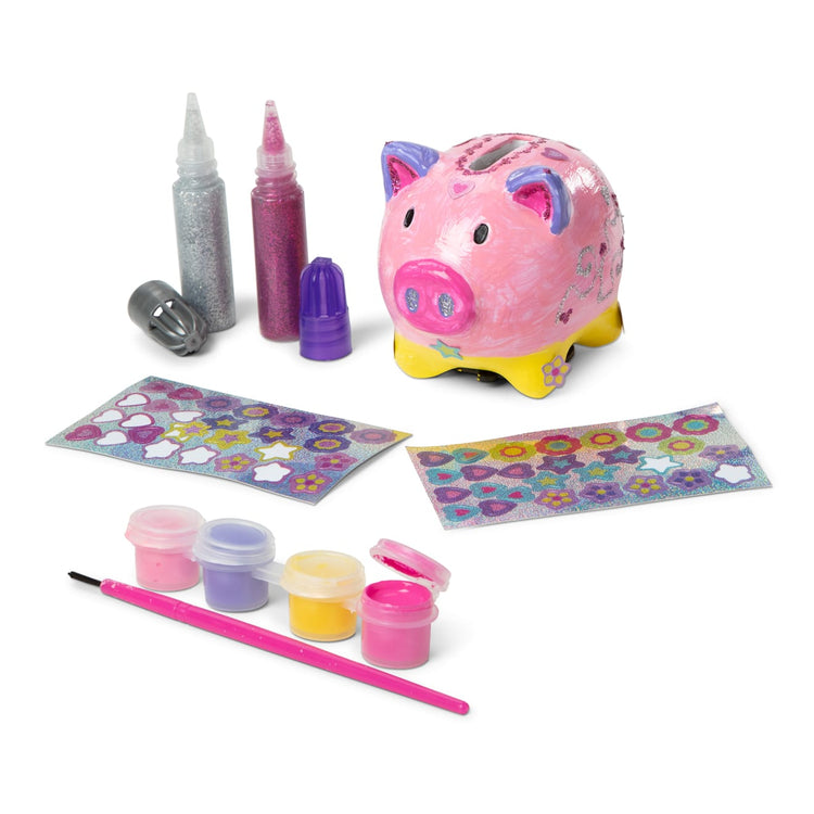The loose pieces of the Melissa & Doug Created by Me! Piggy Bank Craft Kit with 4 Pots of Paint, Brush, Glitter, Stickers