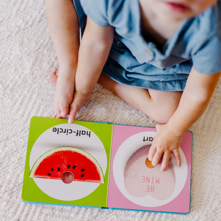A kid playing with the Melissa & Doug Children’s Book – Poke-a-Dot: First Shapes (Board Book with Buttons to Pop)