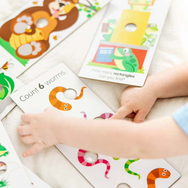 A kid playing with the Melissa & Doug Poke-A-Dot Jumbo Number Learning Cards - 13 Double-Sided Numbers, Shapes, and Colors Cards with Buttons to Pop