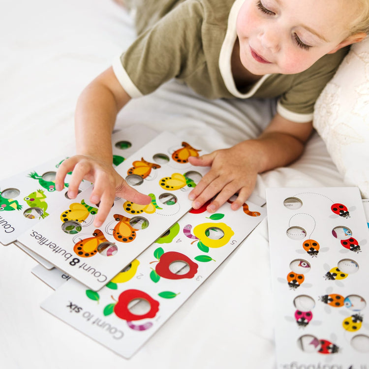 A kid playing with the Melissa & Doug Poke-A-Dot Jumbo Number Learning Cards - 13 Double-Sided Numbers, Shapes, and Colors Cards with Buttons to Pop