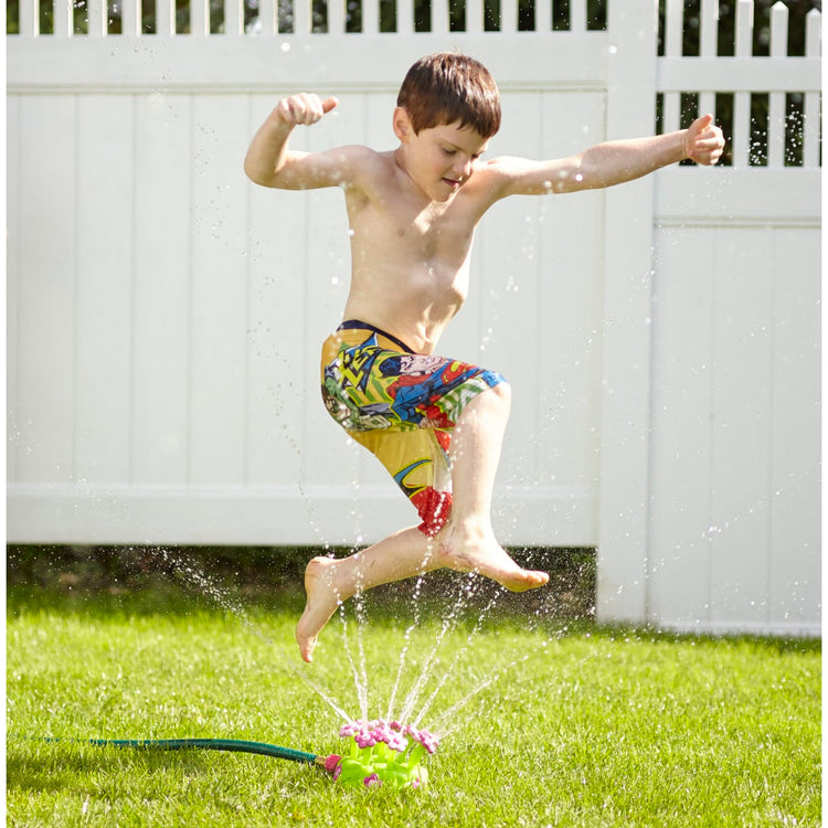 A kid playing with the Melissa & Doug Sunny Patch Pretty Petals Flower Sprinkler Toy With Hose Attachment