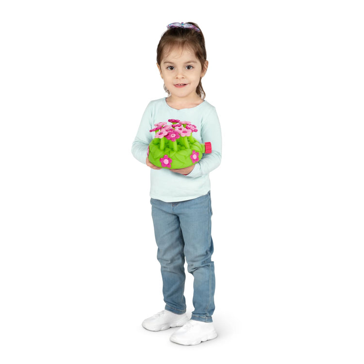 A child on white background with the Melissa & Doug Sunny Patch Pretty Petals Flower Sprinkler Toy With Hose Attachment