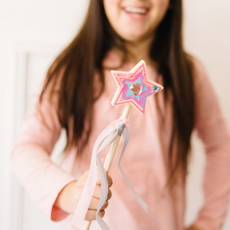 A kid playing with the Melissa & Doug Decorate-Your-Own Wooden Princess Wand Craft Kit