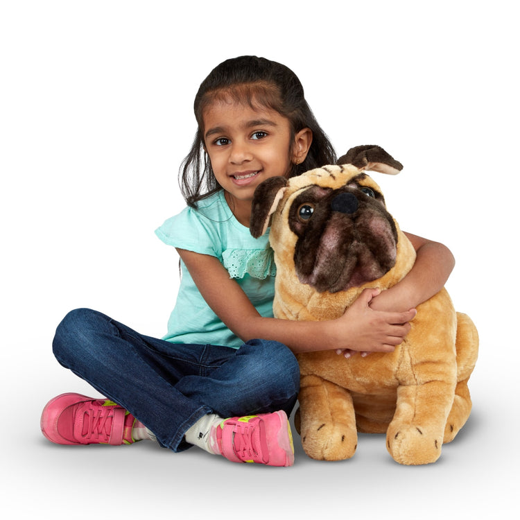 A child on white background with the Melissa & Doug Pug Dog -  Lifelike Stuffed Animal