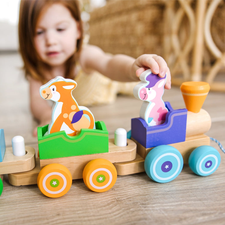 A kid playing with the Melissa & Doug First Play Wooden Rocking Farm Animals Pull Train
