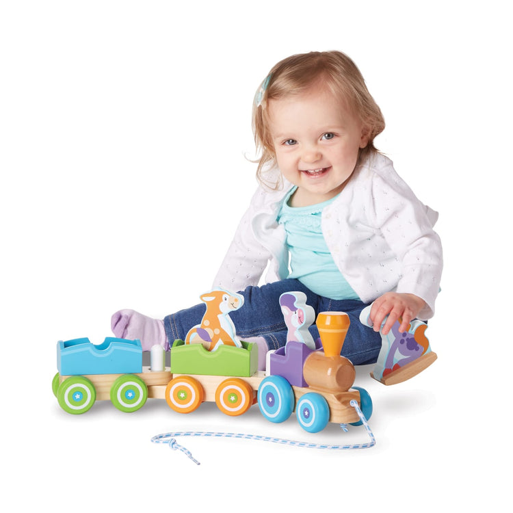 A child on white background with the Melissa & Doug First Play Wooden Rocking Farm Animals Pull Train