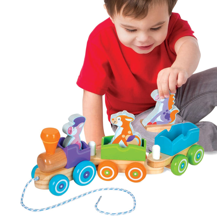 A child on white background with the Melissa & Doug First Play Wooden Rocking Farm Animals Pull Train