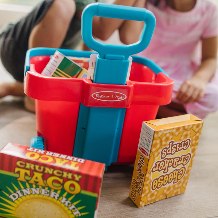 A kid playing with the Melissa & Doug Fill and Roll Grocery Basket Play Set With Play Food Boxes and Cans (11 pcs)