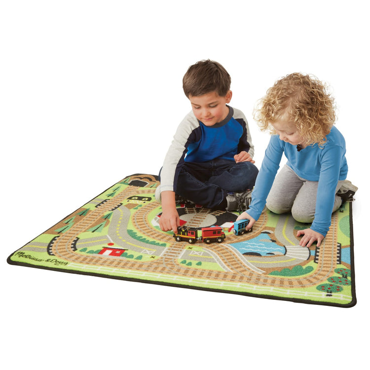 A child on white background with the Melissa & Doug Round the Rails Train Rug With 3 Linking Wooden Train Cars  (39 x 36 inches)
