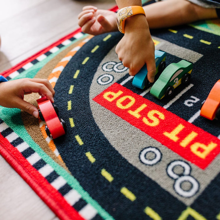 A kid playing with the Melissa & Doug Round the Speedway Race Track Rug With 4 Race Cars (39 x 36 inches)