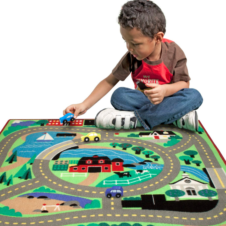 A child on white background with the Melissa & Doug Round the Town Road Rug and Car Activity Play Set With 4 Wooden Cars (39 x 36 inches)