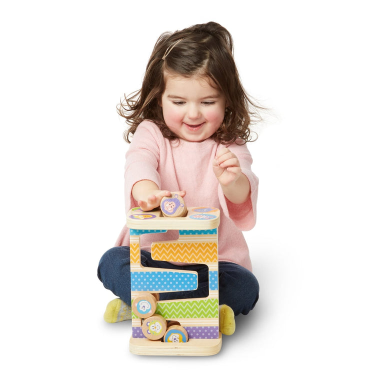 A child on white background with the Melissa & Doug First Play Wooden Safari Zig-Zag Tower With 4 Rolling Pieces