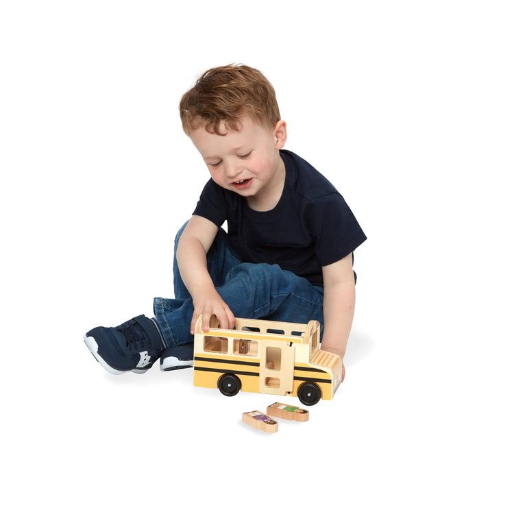 A child on white background with the Melissa & Doug School Bus Wooden Play Set With 7 Play Figures