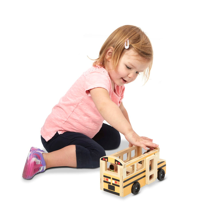 A child on white background with the Melissa & Doug School Bus Wooden Play Set With 7 Play Figures
