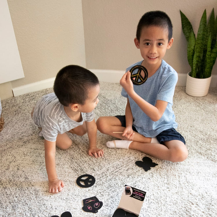 A kid playing with the Melissa & Doug Scratch Art® Box of 125 Friendship-Themed Shaped Notes in Desktop Dispenser (Approx. 3.5” x 3.5” Each Note)