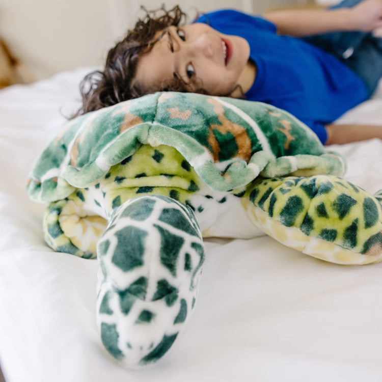 A kid playing with the Melissa & Doug Giant Sea Turtle - Lifelike Stuffed Animal (nearly 3 feet long)
