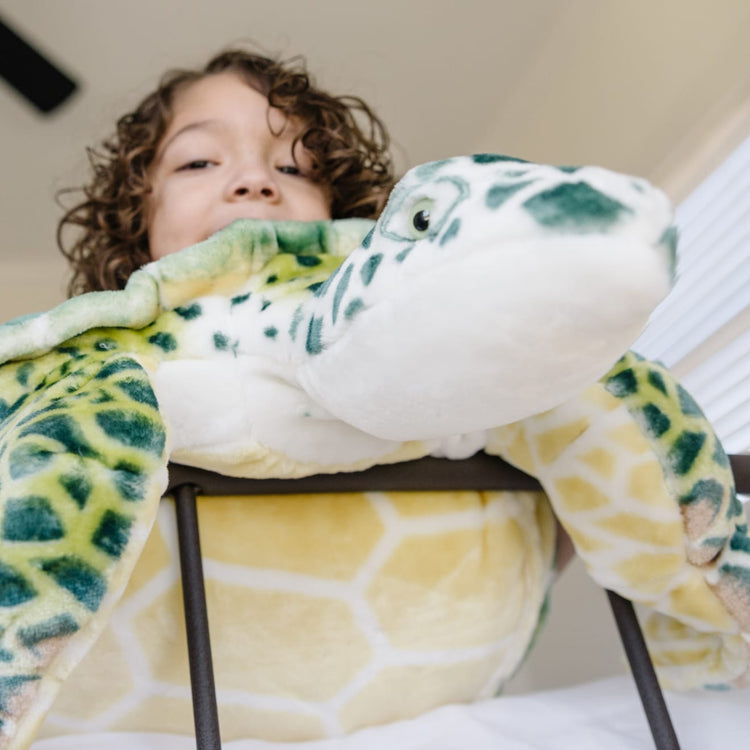 A kid playing with the Melissa & Doug Giant Sea Turtle - Lifelike Stuffed Animal (nearly 3 feet long)
