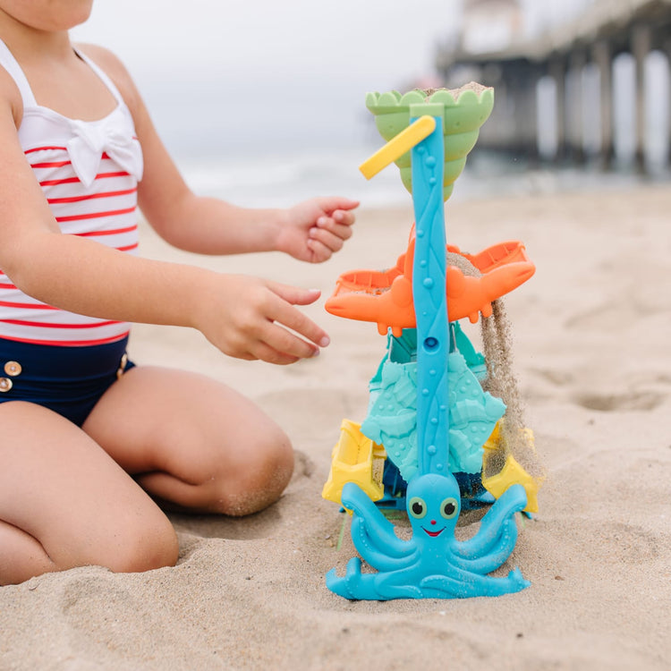 A kid playing with the Melissa & Doug Seaside Sidekicks Sand-and-Water Sifting Funnel