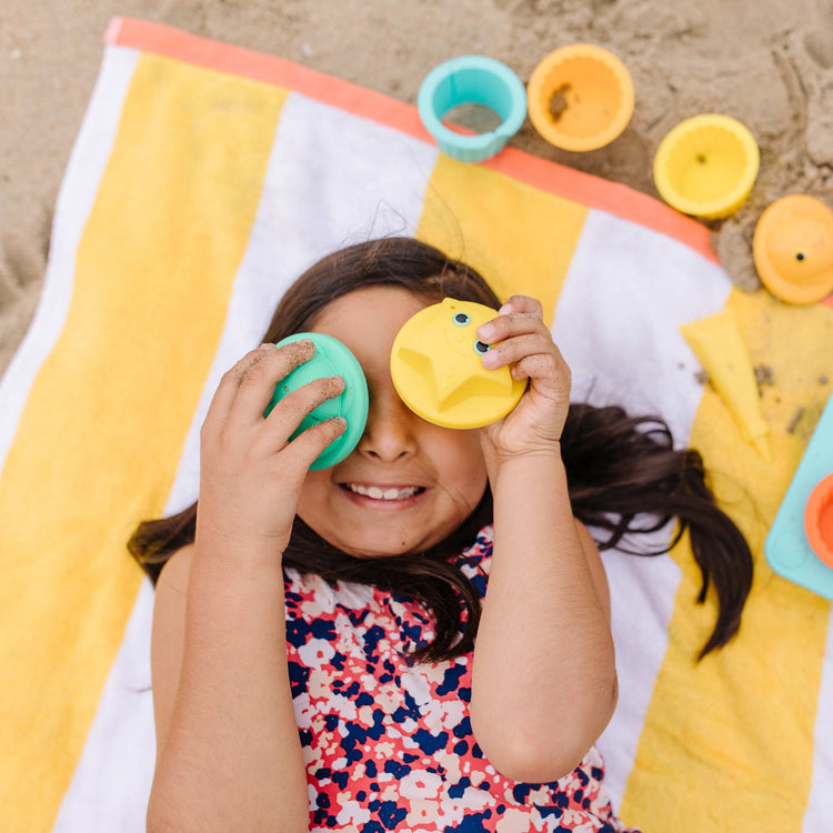 A kid playing with the Melissa & Doug Sunny Patch Seaside Sidekicks Sand Cupcake Play Set