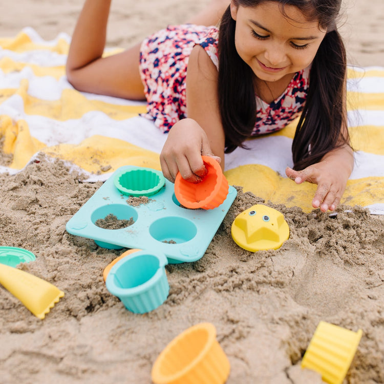 A kid playing with the Melissa & Doug Sunny Patch Seaside Sidekicks Sand Cupcake Play Set