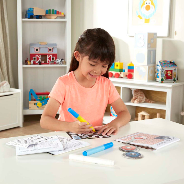 A kid playing with the Melissa & Doug On the Go Secret Decoder Deluxe Activity Set and Super Sleuth Toy