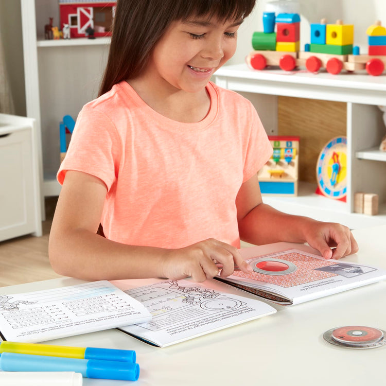 A kid playing with the Melissa & Doug On the Go Secret Decoder Deluxe Activity Set and Super Sleuth Toy