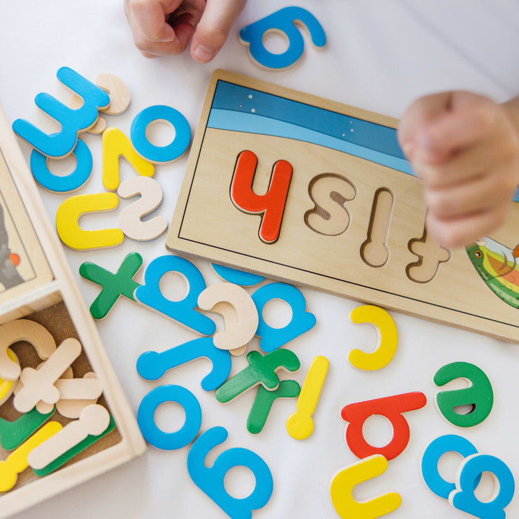 A kid playing with the Melissa & Doug See & Spell Wooden Educational Toy With 8 Double-Sided Spelling Boards and 64 Letters