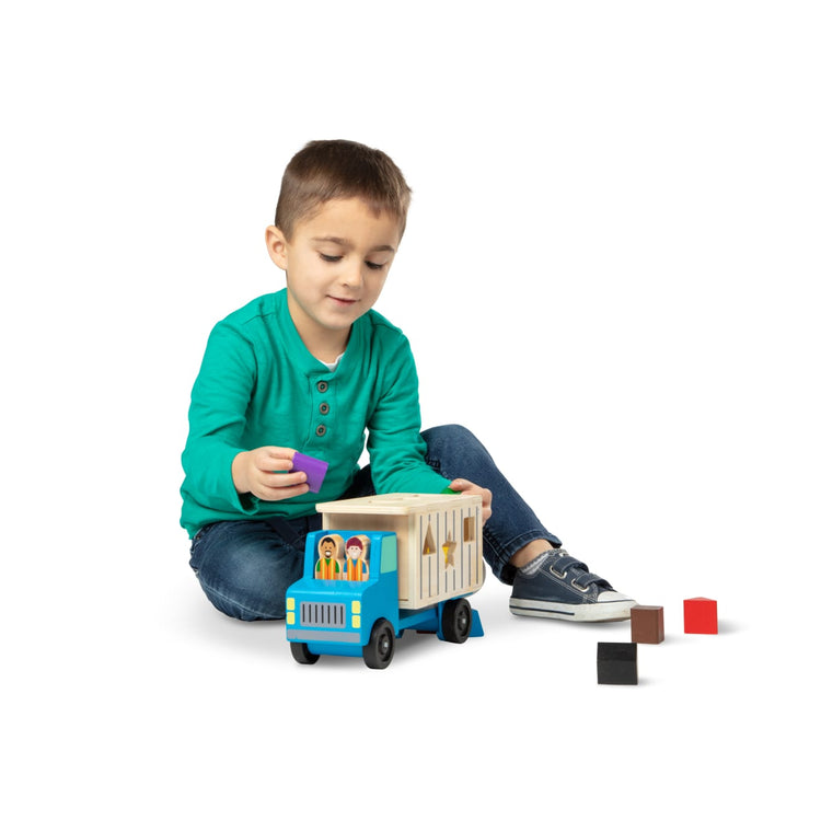 A child on white background with the Melissa & Doug Shape-Sorting Wooden Dump Truck Toy With 9 Colorful Shapes and 2 Play Figures