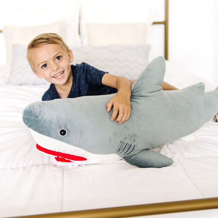 A kid playing with the Melissa & Doug Giant Shark - Lifelike Stuffed Animal (over 3 feet long)