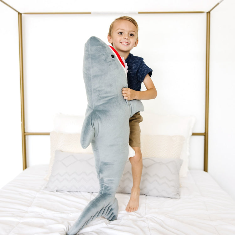A kid playing with the Melissa & Doug Giant Shark - Lifelike Stuffed Animal (over 3 feet long)