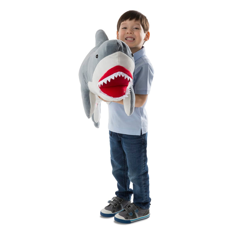 A child on white background with the Melissa & Doug Giant Shark - Lifelike Stuffed Animal (over 3 feet long)