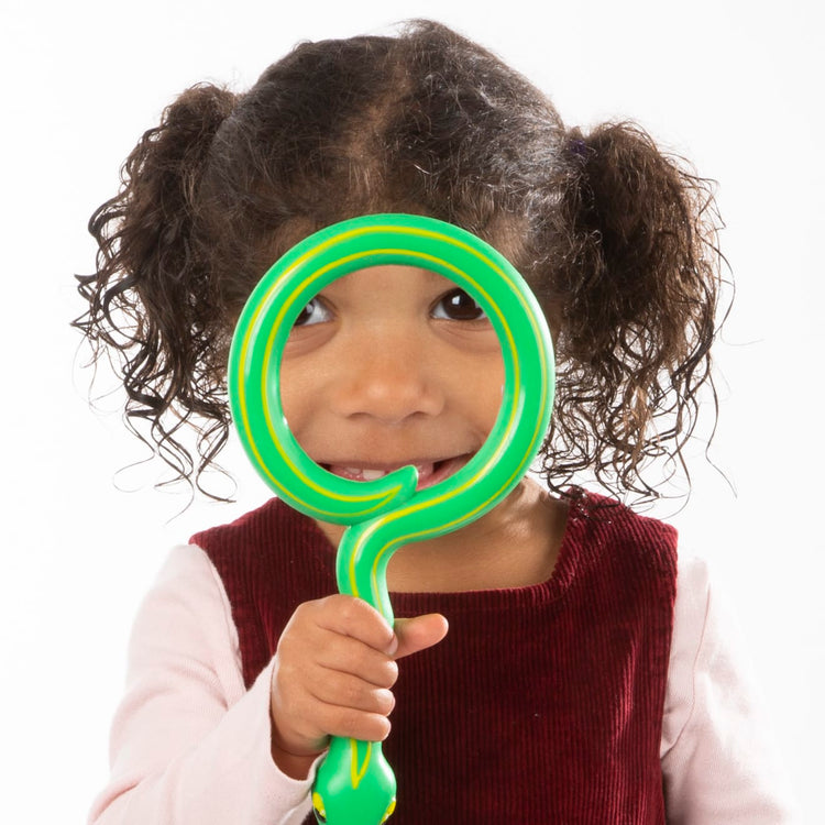 A child on white background with the Melissa & Doug Sunny Patch Shimmy Snake Magnifying Glass With Shatterproof Lens
