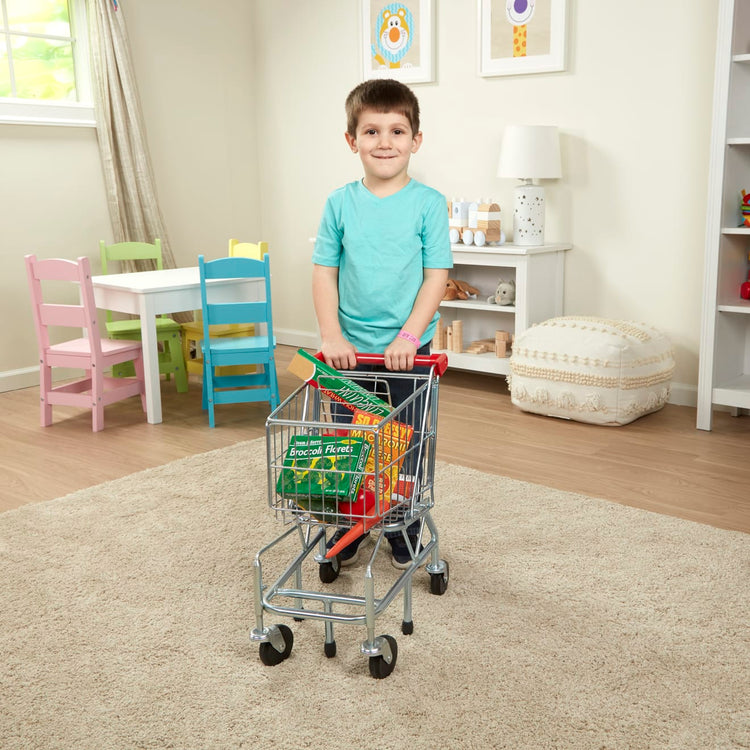 A kid playing with the Melissa & Doug Toy Shopping Cart With Sturdy Metal Frame