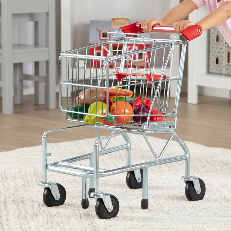 A kid playing with the Melissa & Doug Toy Shopping Cart With Sturdy Metal Frame