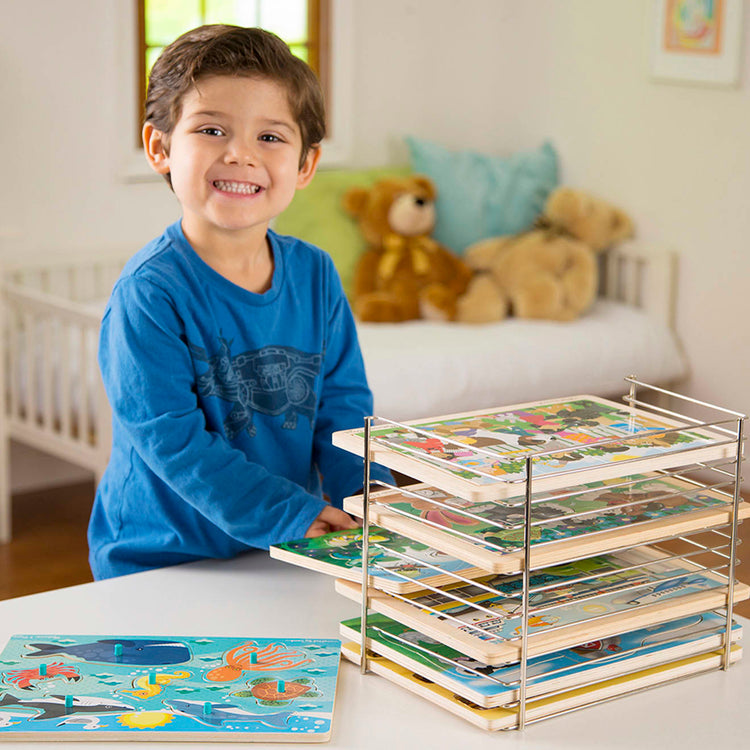 A kid playing with the Melissa & Doug Puzzle Storage Rack - Wire Rack Holds 12 Puzzles